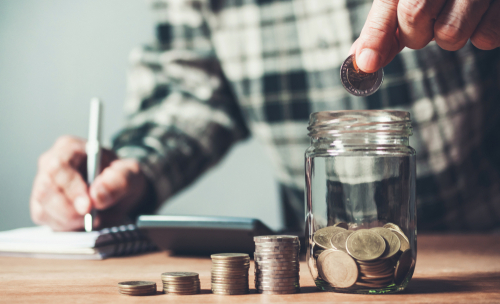 Business,Man,Putting,Coin,In,Glass,Bottle,Saving,Bank,And